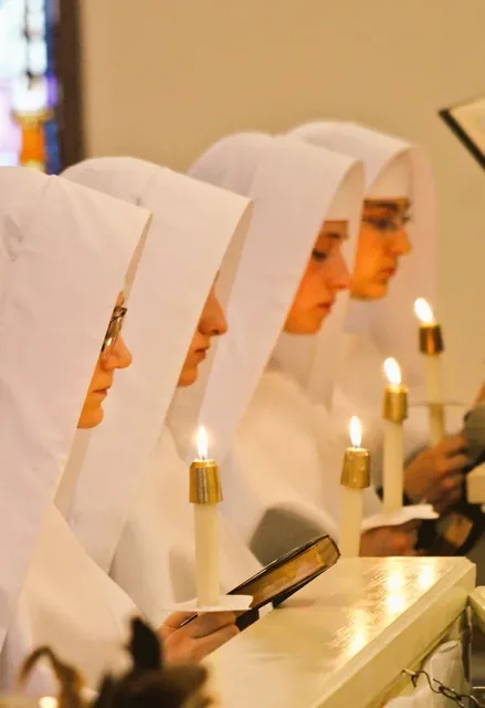 Novices with candles during a ceremony in the convent chapel.